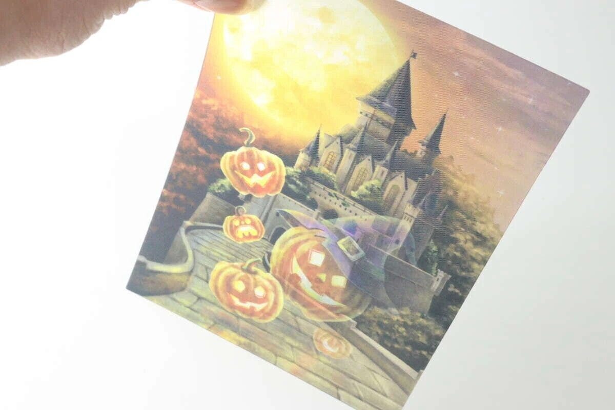 手に持たれたレンチキュラーアートの夜のハロウィン城の絵柄