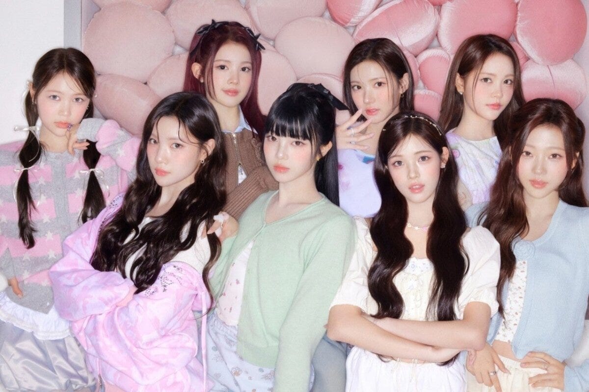 9人組ガールズグループ「Hearts2Hearts」がピンクの背景でポーズをとっている