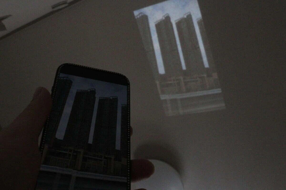 スマートフォンから壁に高層ビル群の映像を投影している スマートフォンから壁に高層ビル群の映像を投影している