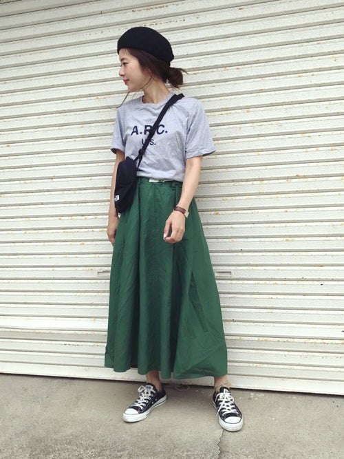ロゴTシャツにグリーンギャザースカートを履いた女性