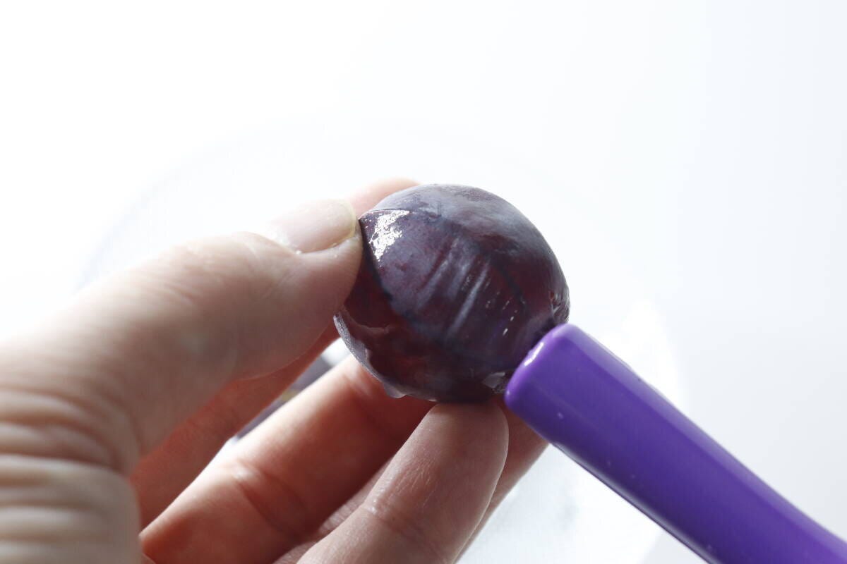 ぶどうの茎の穴に皮むき器のワイヤーを差し込んでいる手元