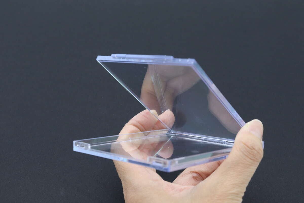 透明なトレカ用クリアケースの蓋を開けている手のアップ