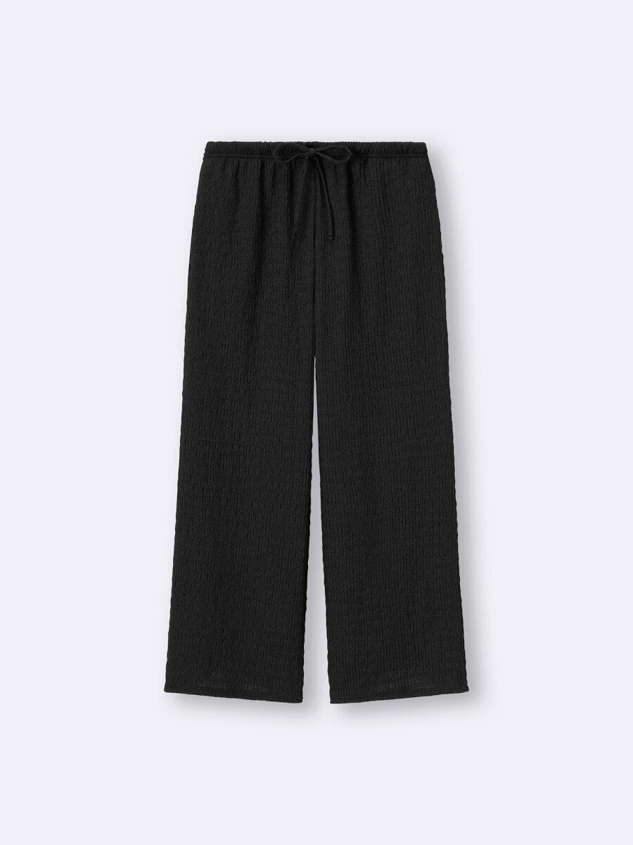 黒のシャーリングアンクルパンツ。フレアシルエットでスタイルアップ効果。