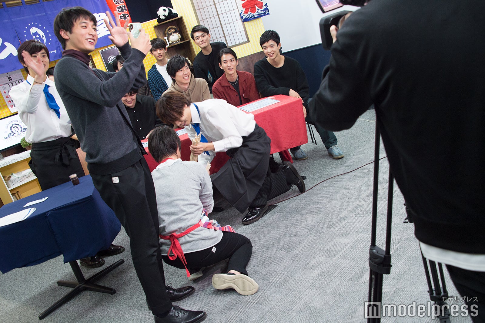 松岡広大のテレビ電話に対応する小関裕太の後ろで床にばらまかれた割り箸を片付ける太田将熙、細田佳央太（C）モデルプレス