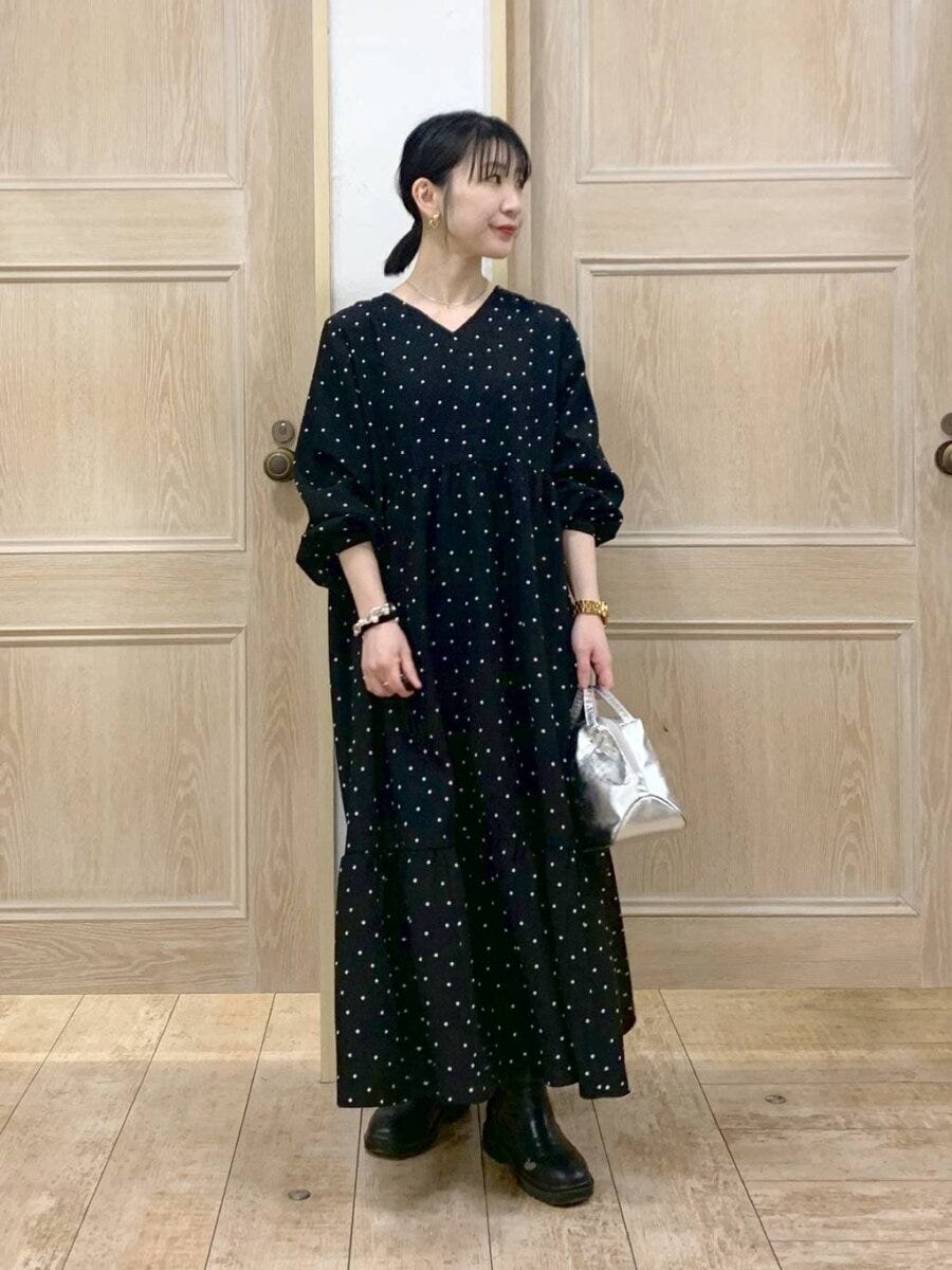 黒のドット柄ワンピースを着てシルバーバッグを持つ女性 黒のドット柄ワンピースを着てシルバーバッグを持つ女性