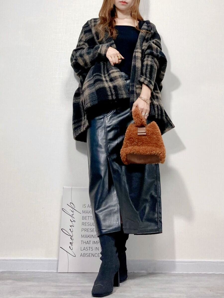 チェック柄アウターと黒スカート、黒ブーツを履いた女性の全身コーディネート