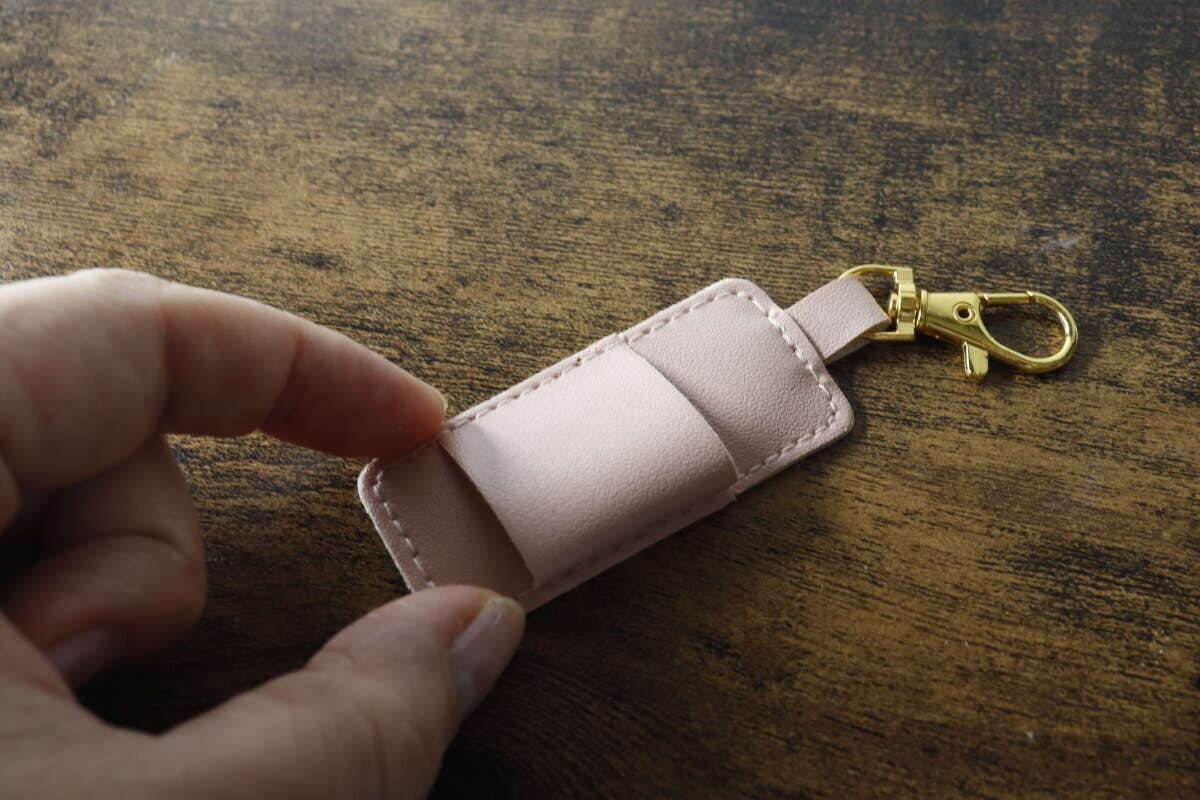 女性の指がピンクのペンホルダーのベルト部分を押している 女性の指がピンクのペンホルダーのベルト部分を押している