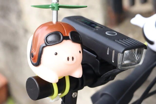 自転車ハンドル延長ブラケットにライトと豚がついている