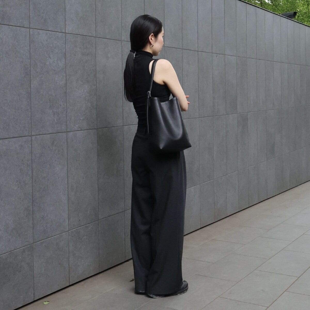 黒いノースリーブとワイドパンツを着用し、後ろを向く女性の全身 黒いノースリーブとワイドパンツを着用し、後ろを向く女性の全身