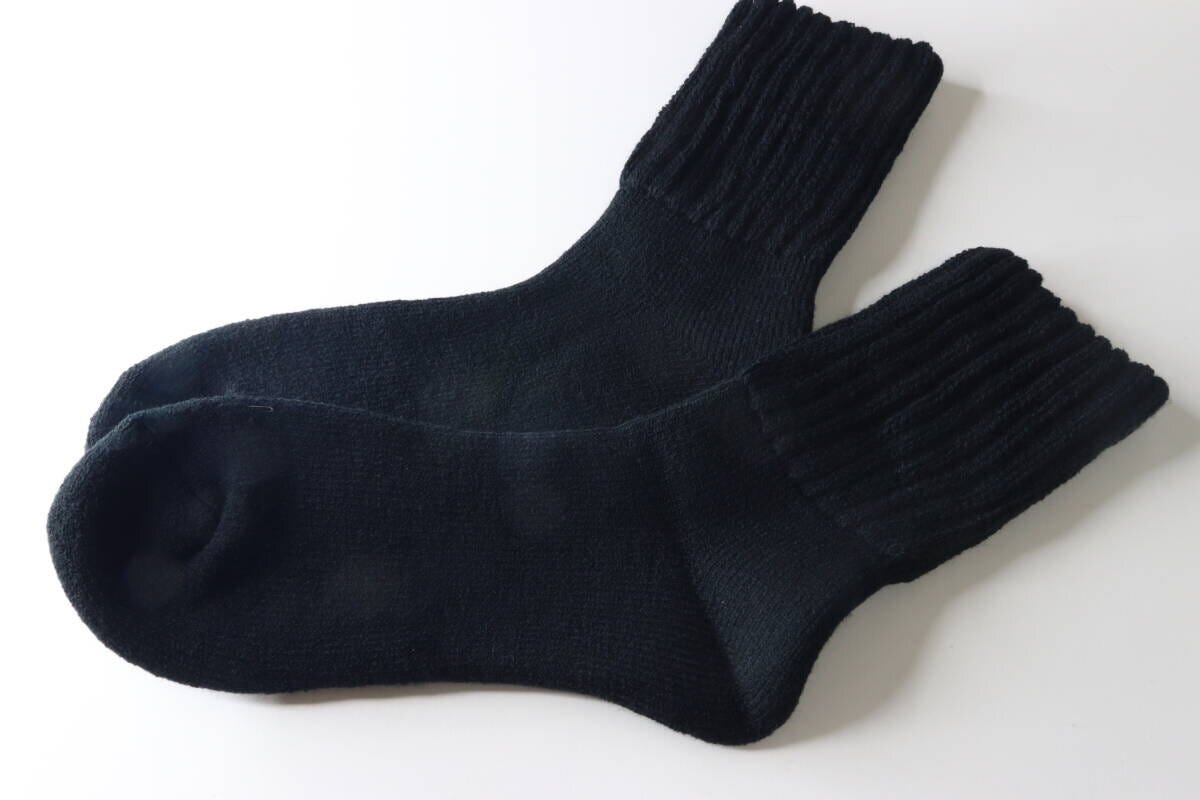 白い背景に並べられた黒い裏起毛パイルソックス2足。