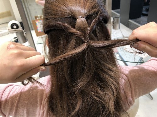 くるりんぱした毛束を2つに分けて、ギューっと引っぱり最初に作ったハーフアップの位置に近づけます。