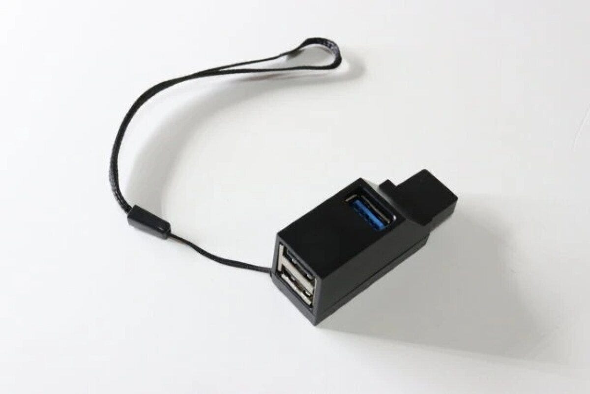 黒いUSBハブとストラップが白い背景に置かれている 黒いUSBハブとストラップが白い背景に置かれている