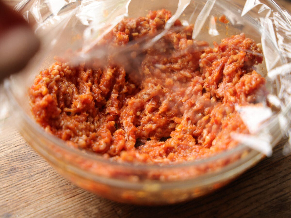 調味料と混ぜ合わせたひき肉をラップで覆い、電子レンジで加熱する準備をしている。 調味料と混ぜ合わせたひき肉をラップで覆い、電子レンジで加熱する準備をしている。