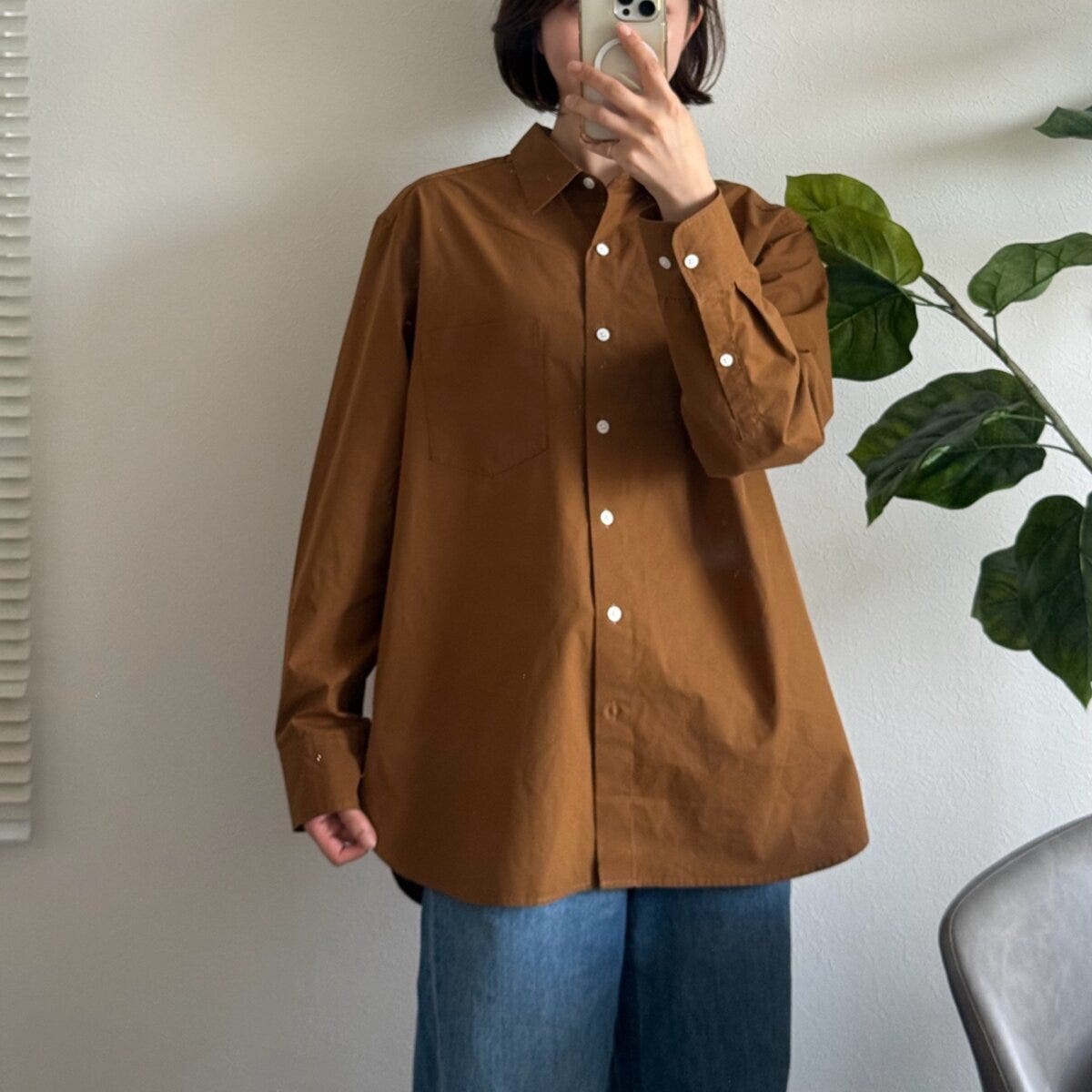 ブラウンシャツを着た女性がスマホで自撮り