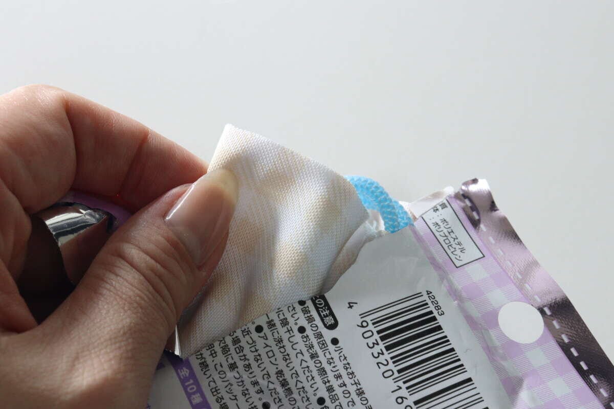 女性の手がダイソーのサガラ刺繍プチ巾着をパッケージから取り出している様子 女性の手がダイソーのサガラ刺繍プチ巾着をパッケージから取り出している様子