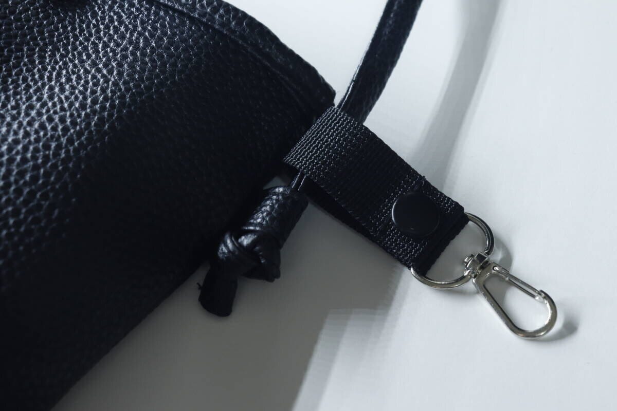 黒い細いショルダーベルトのバッグに小物ホルダーを取り付けている