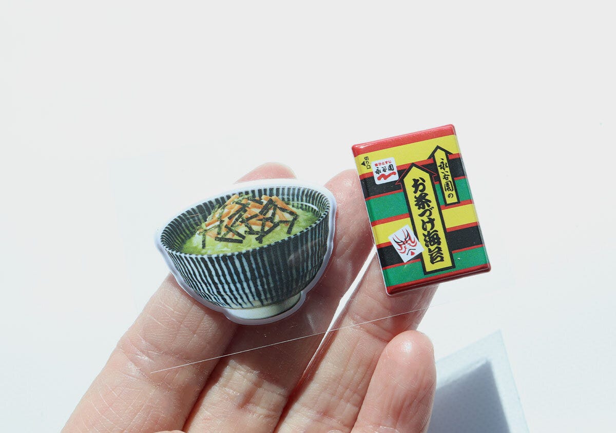 お茶づけ海苔ぷっくりシール お茶碗とお茶づけ海苔小袋モチーフのぷっくりシール2点を手のひらに乗せた様子