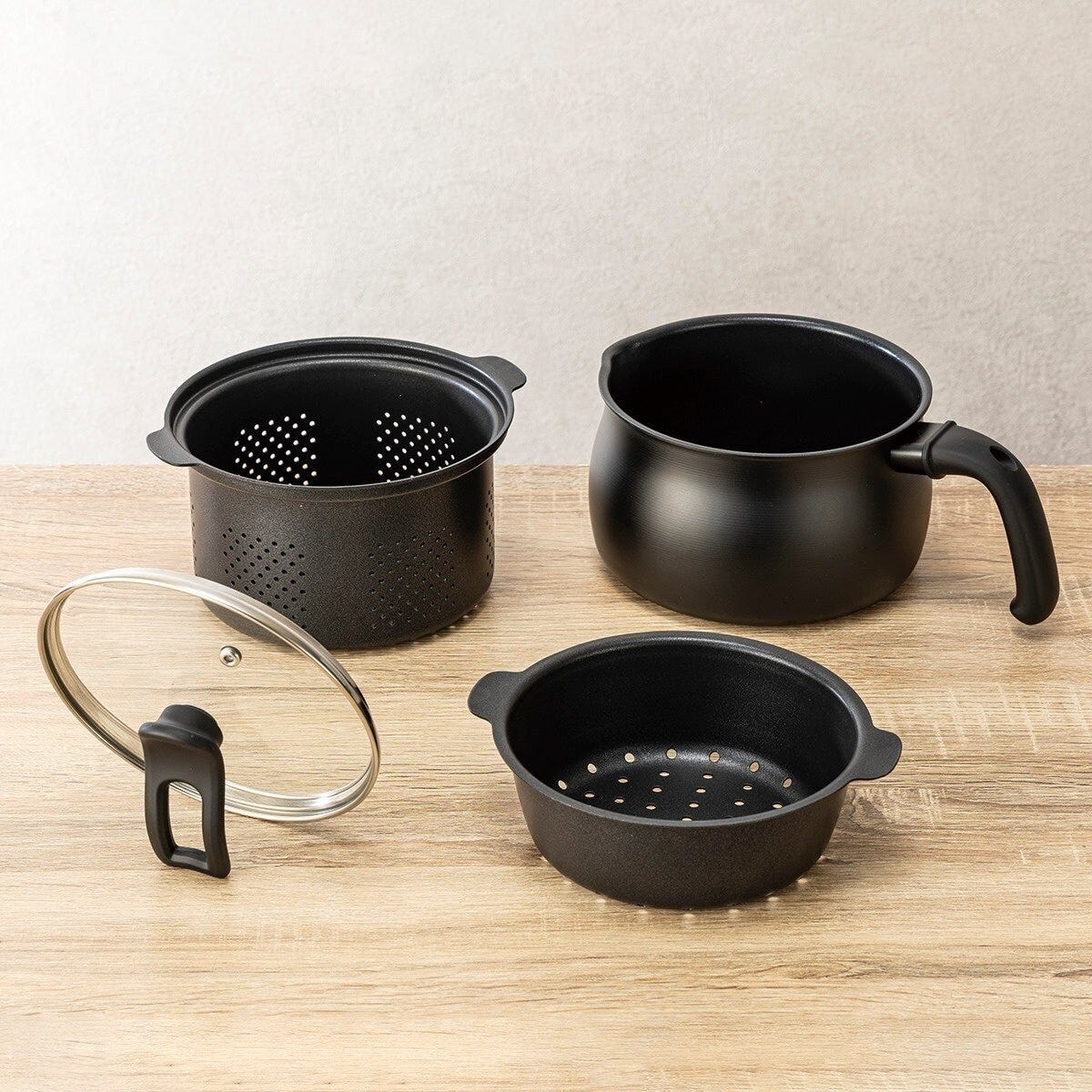 黒いマルチポットの本体と付属品が木製テーブルに並べられている
