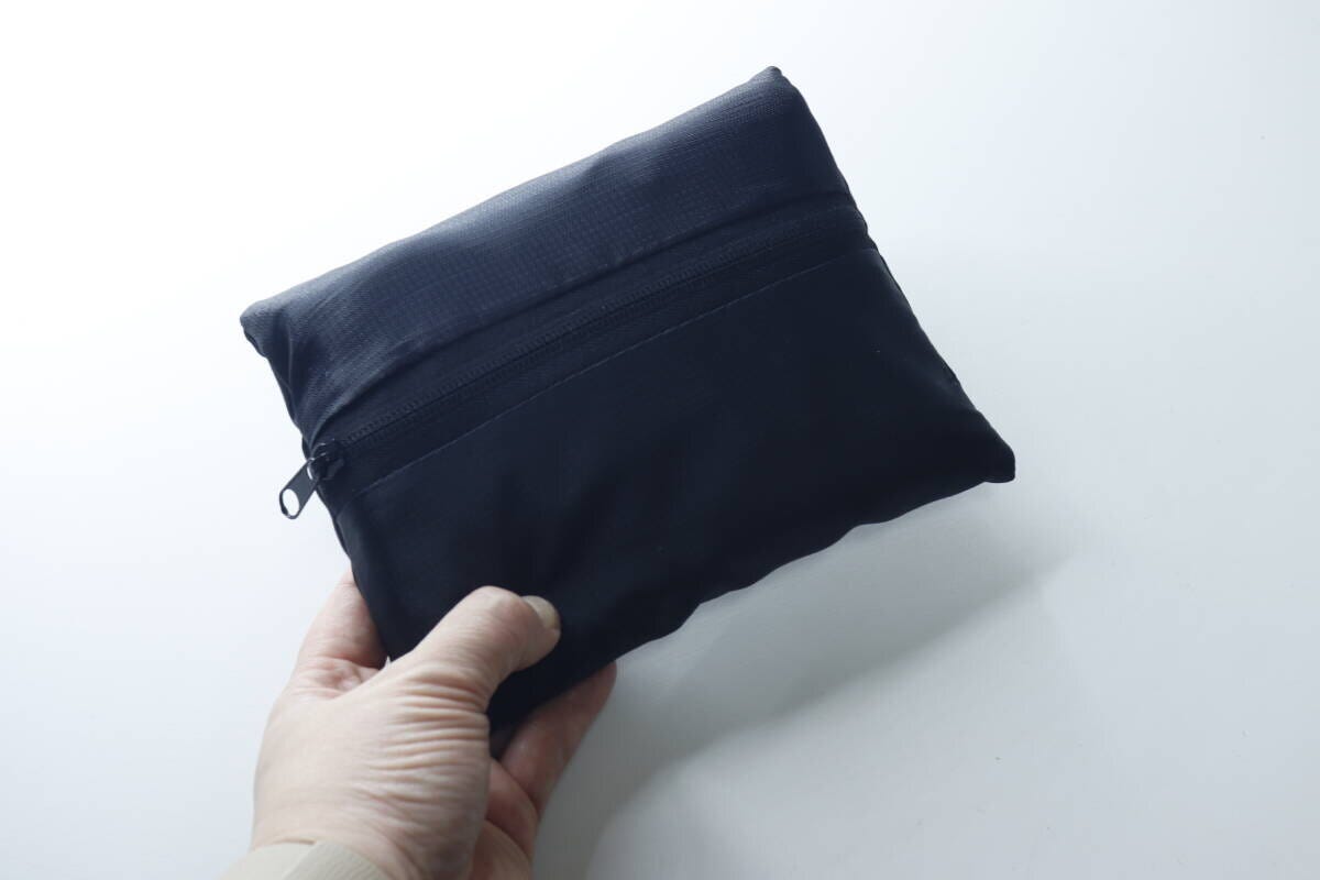 手でコンパクトにたたまれた黒いバッグを持っている