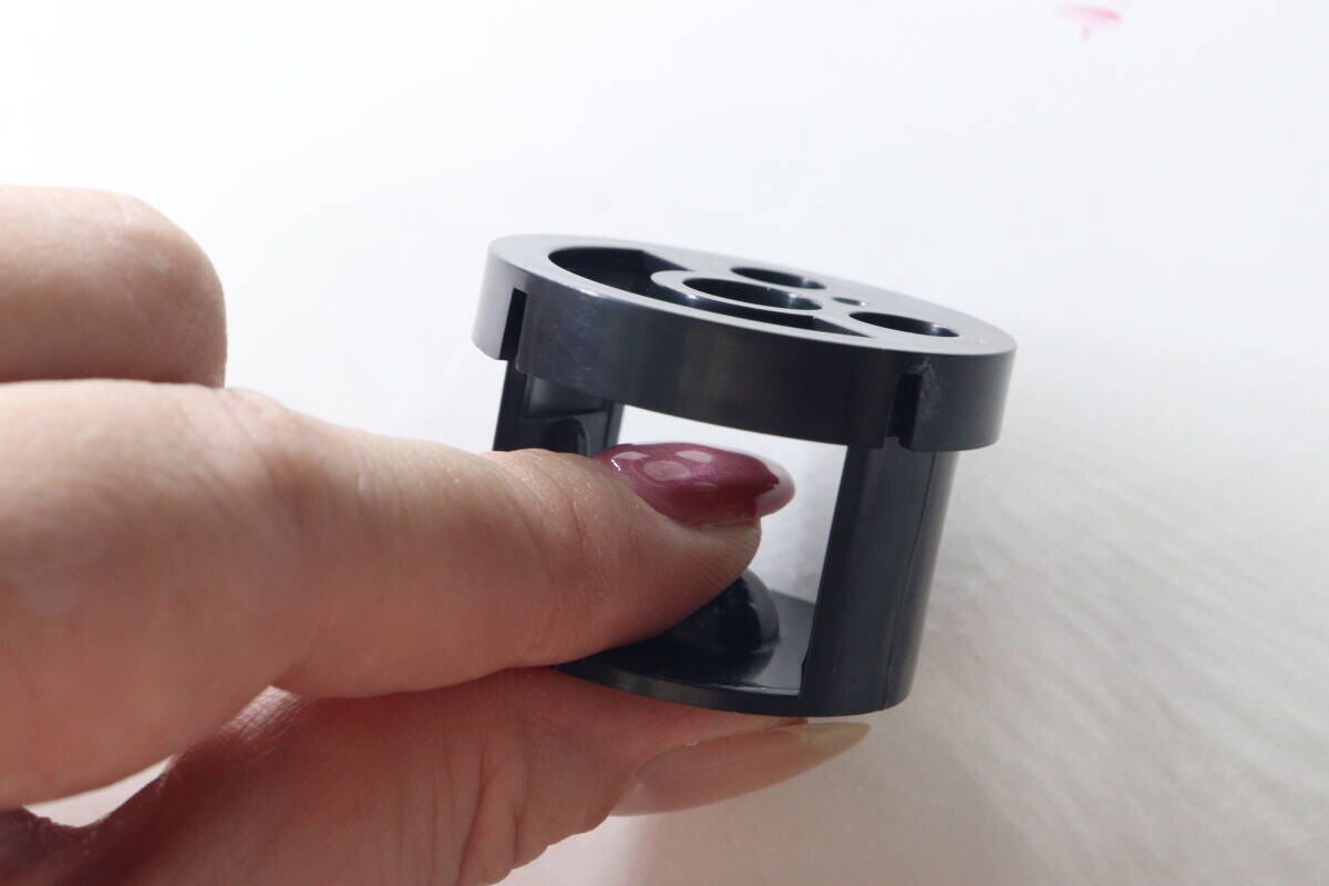 赤いネイルを塗った指をスタンドの横穴に入れている様子
