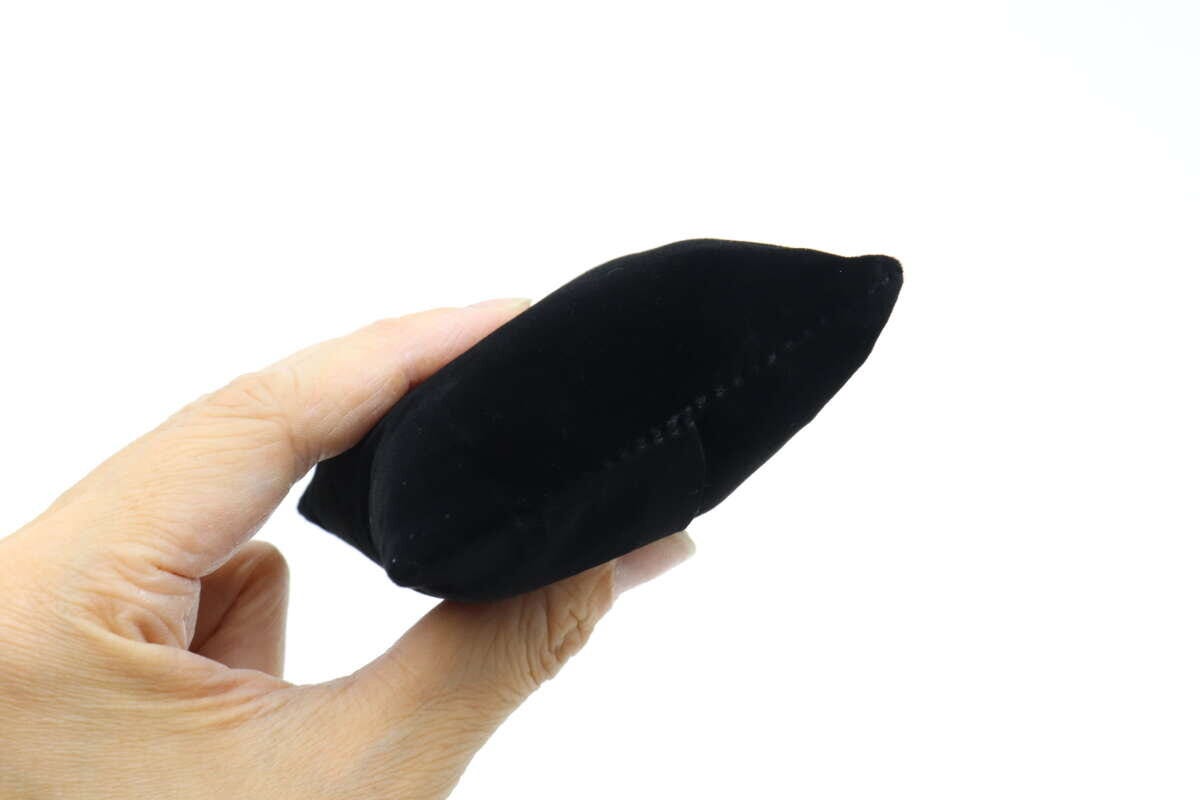 黒いベロア素材の腕時計用クッションを手に持つ