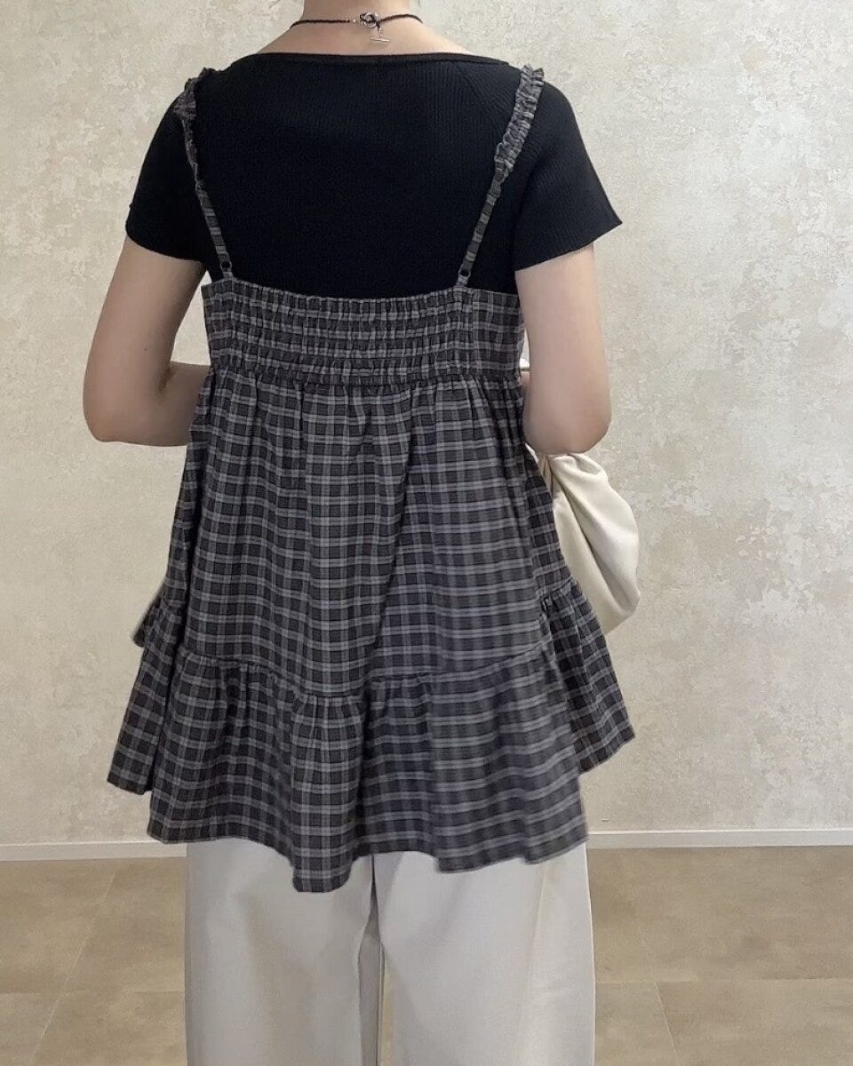 黒Tシャツと白パンツにチェックキャミを重ね着した女性の後ろ姿