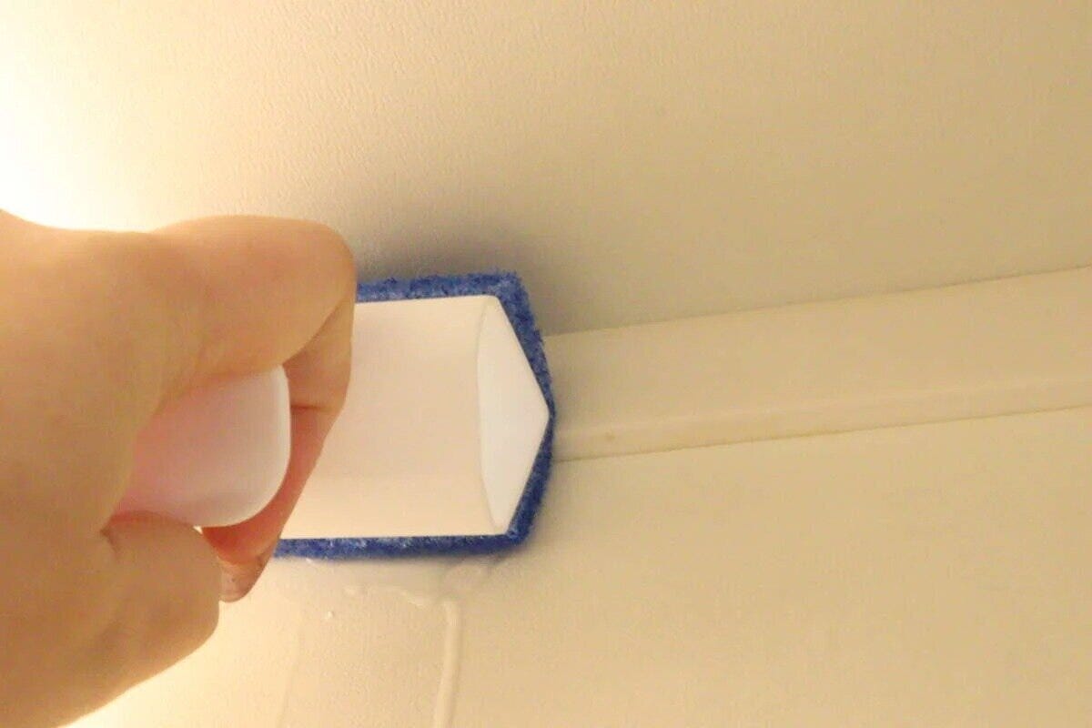 手で浴室ブラシを使い浴室の床と壁の境目を掃除している様子 手で浴室ブラシを使い浴室の床と壁の境目を掃除している様子