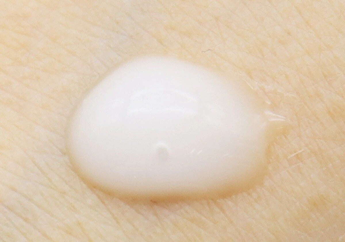 手の甲に白い美容液が1滴乗っているクローズアップ 手の甲に白い美容液が1滴乗っているクローズアップ
