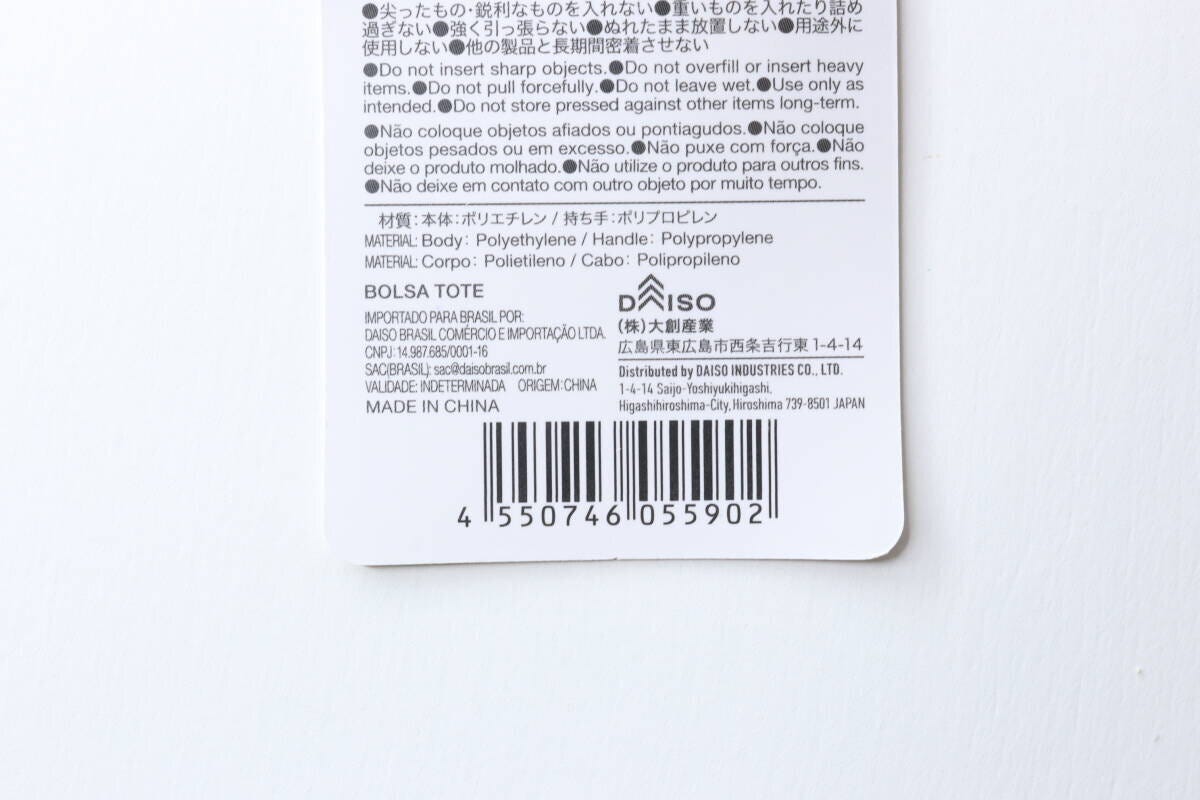 ダイソーのトートバッグのタグ。JANコードや素材、使用上の注意書きが記載されている