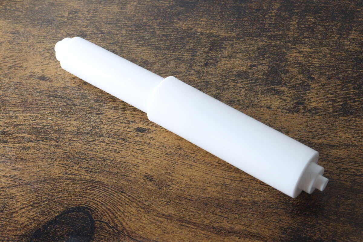 木目調のテーブルに置かれた白いトイレットペーパー替え芯ホルダー 木目調のテーブルに置かれた白いトイレットペーパー替え芯ホルダー