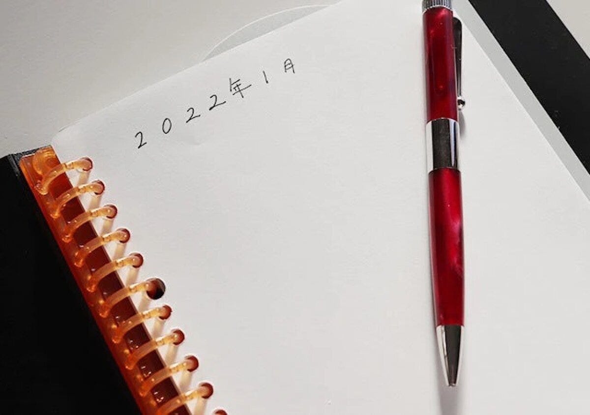 ノートに「2022年1月」と書かれ、赤いペンが置かれている