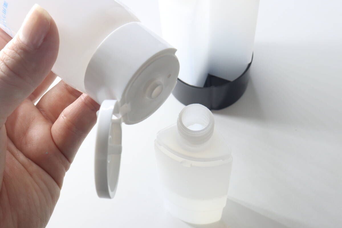 白い詰め替えボトルに化粧水を注ぎ入れている 白い詰め替えボトルに化粧水を注ぎ入れている