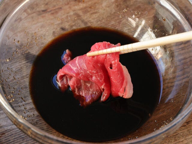 ボウルに調味料を混ぜたら、薄切り牛肉を1枚ずつくぐらせる。