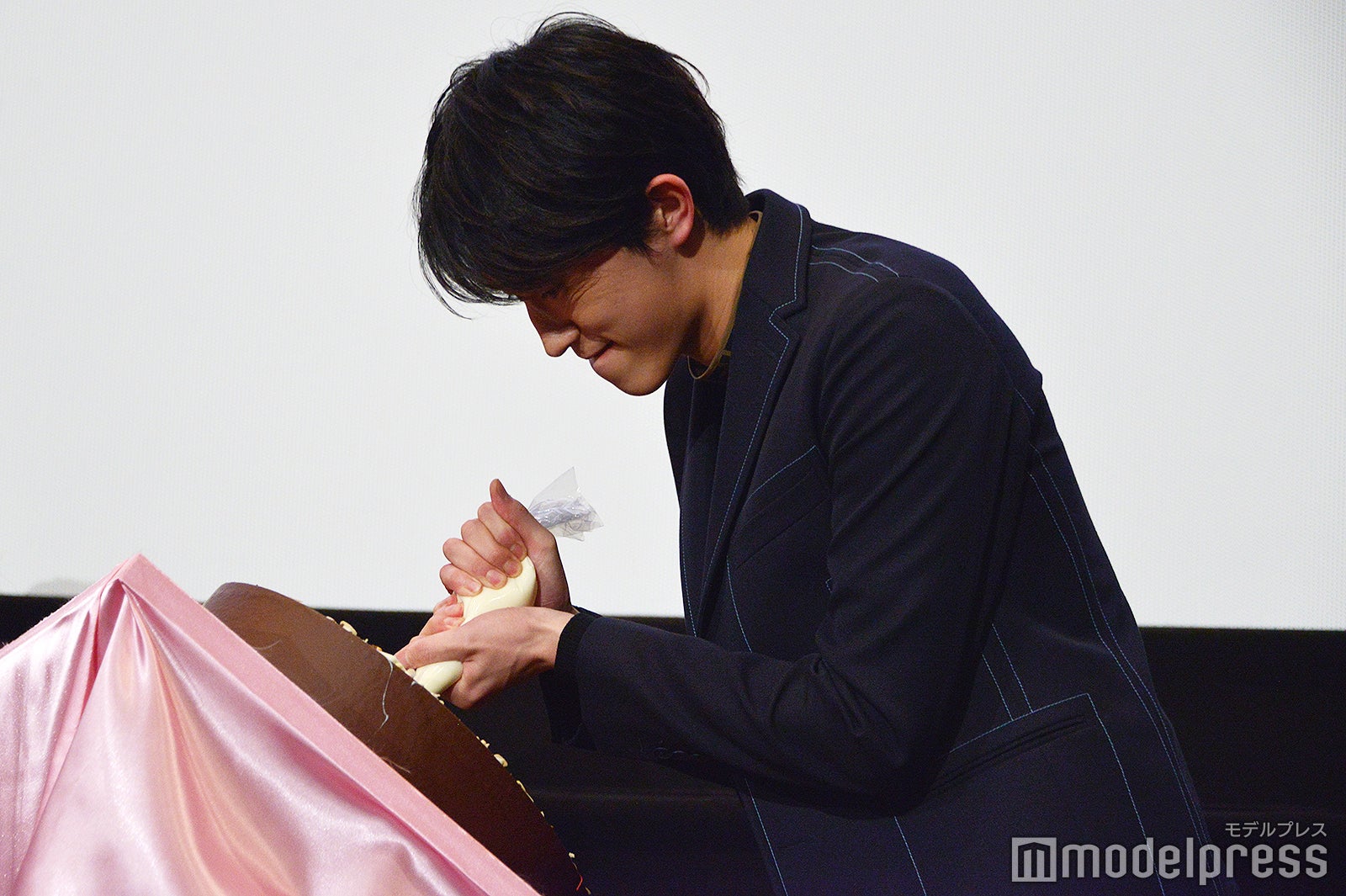 顔をしかめながらメッセージを描く杉野遥亮（C）モデルプレス