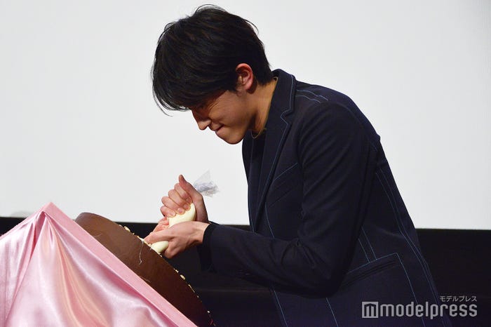 顔をしかめながらメッセージを描く杉野遥亮(C)モデルプレス