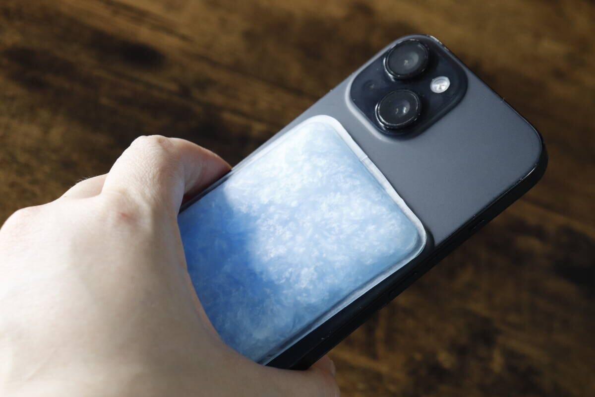 スマートフォンの背面に青い冷却パッドを貼り付けている様子 スマートフォンの背面に青い冷却パッドを貼り付けている様子