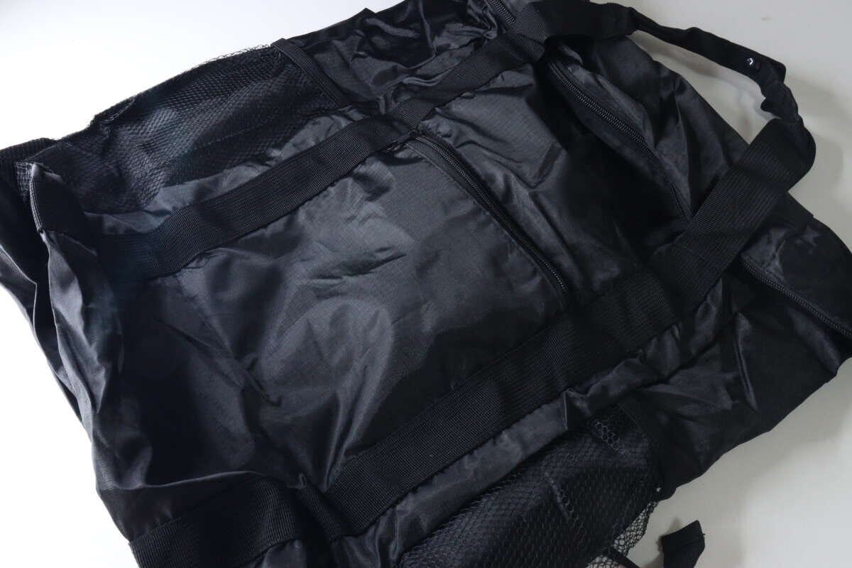 黒いトート型バックパックが広げられた状態。メッシュポケットやファスナー付きポケットが見える。