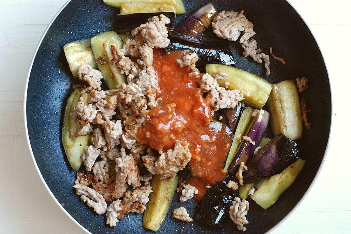 フライパンで炒めたなすとひき肉に、味噌ケチャップの調味料を加えて混ぜ合わせる直前の様子