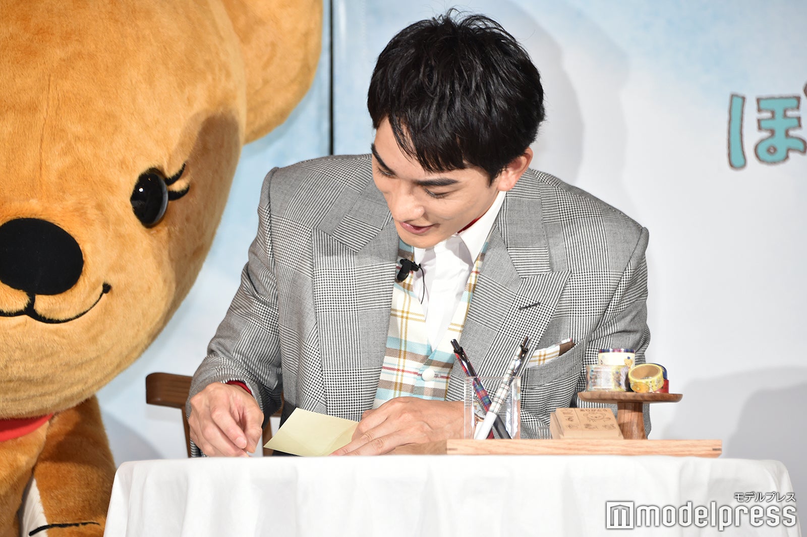 切手を貼る町田啓太を覗くぽすくま（C）モデルプレス