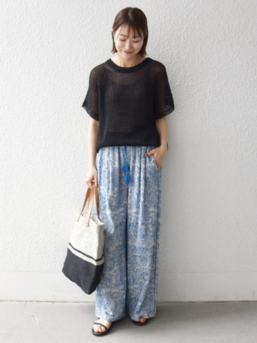 透け感黒ニットと青柄ワイドパンツ、トートバッグを持った女性 透け感黒ニットと青柄ワイドパンツ、トートバッグを持った女性