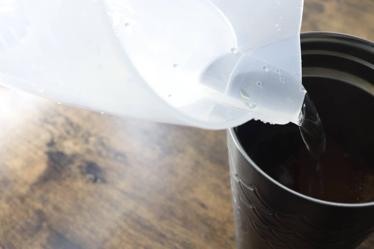 計量カップから黒いタンブラーへお湯を注いでいる様子 計量カップから黒いタンブラーへお湯を注いでいる様子