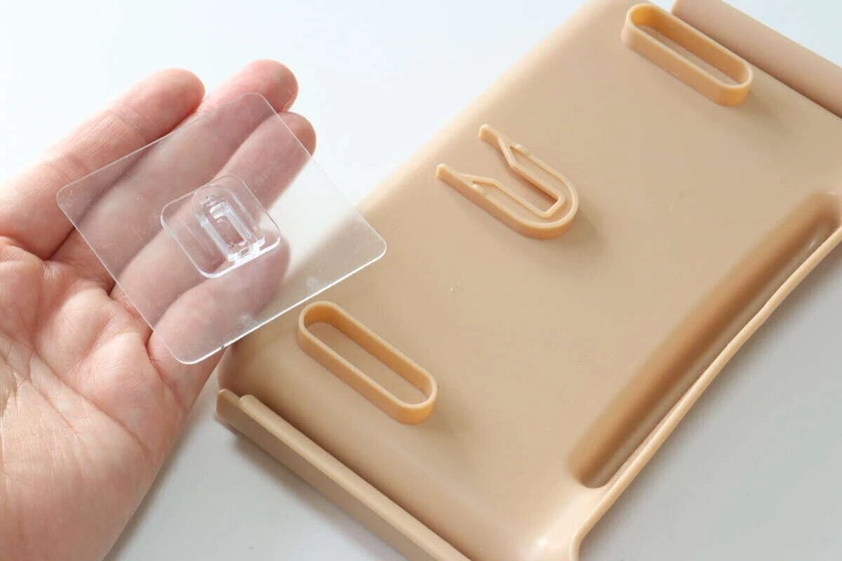 スポンジホルダー(水切りネット用)の設置用ツメ付きシートを手に持つ スポンジホルダー(水切りネット用)の設置用ツメ付きシートを手に持つ
