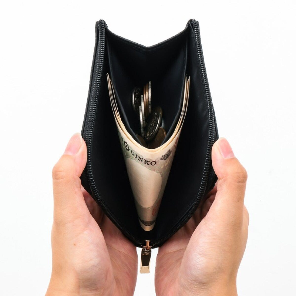 ATAOミニ財布BLACKを開いた中身(札と小銭収納) BLACKのATAOミニ財布を両手でL字に大きく開き、内側に折りたたんだ1万円札と小銭が収まっている様子の正面写真
