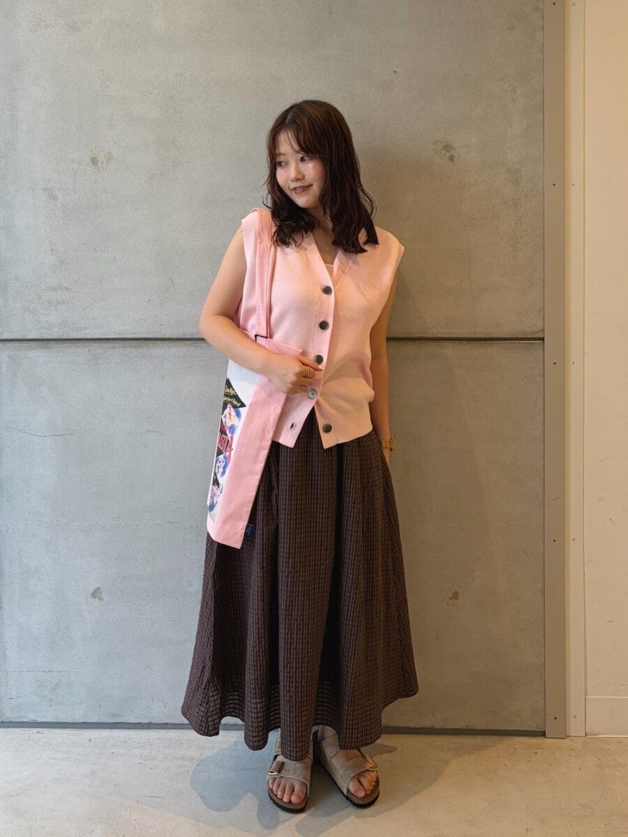 ピンクのニットベストとブラウンフレアスカートの女性 ピンクのニットベストとブラウンフレアスカートの女性