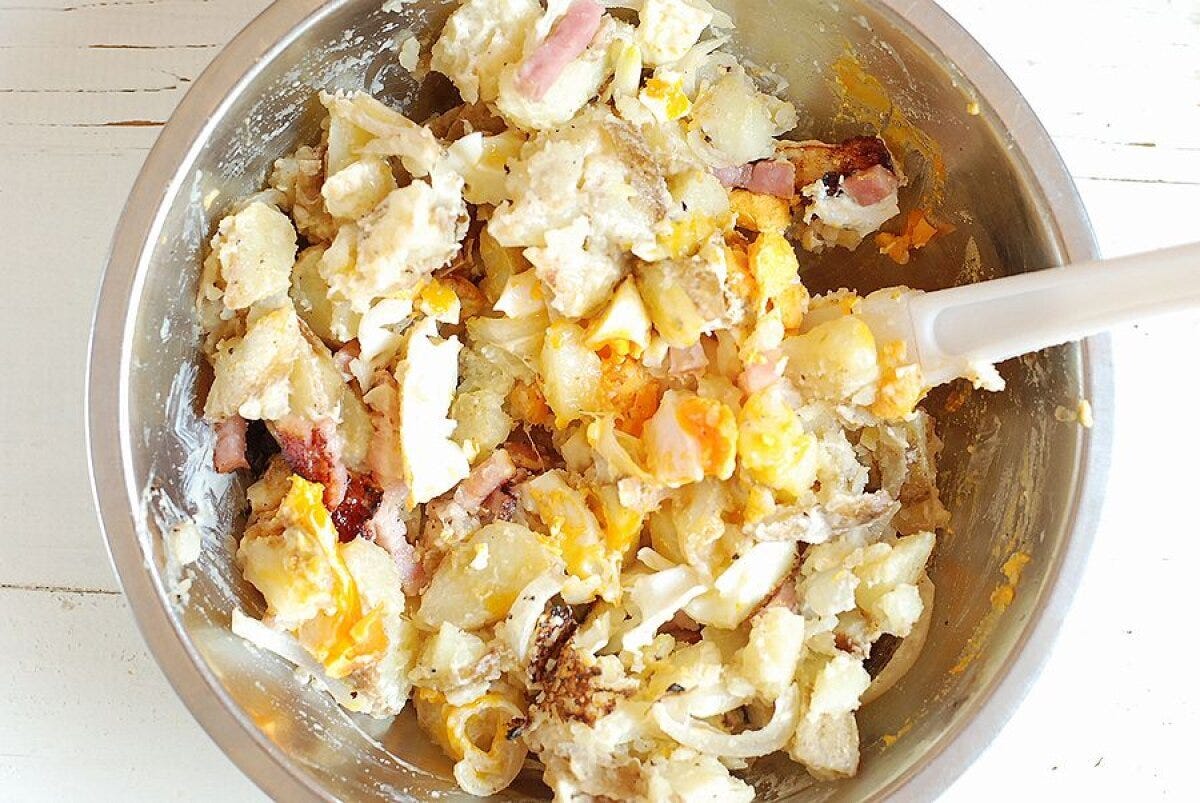 ボウルでじゃがいもとベーコンと半熟目玉焼きを混ぜ合わせた様子