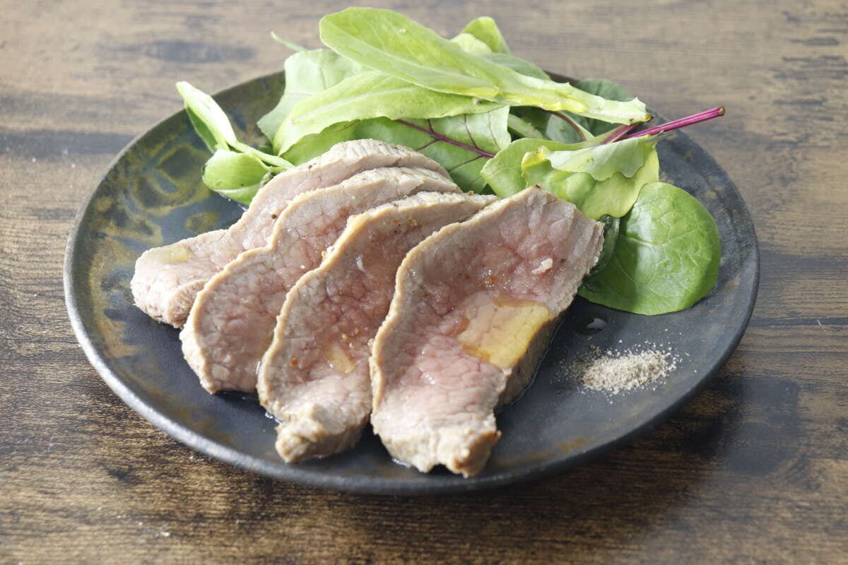 皿に盛り付けられた牛のたたきとベビーリーフにオリーブオイルがかかっている 皿に盛り付けられた牛のたたきとベビーリーフにオリーブオイルがかかっている