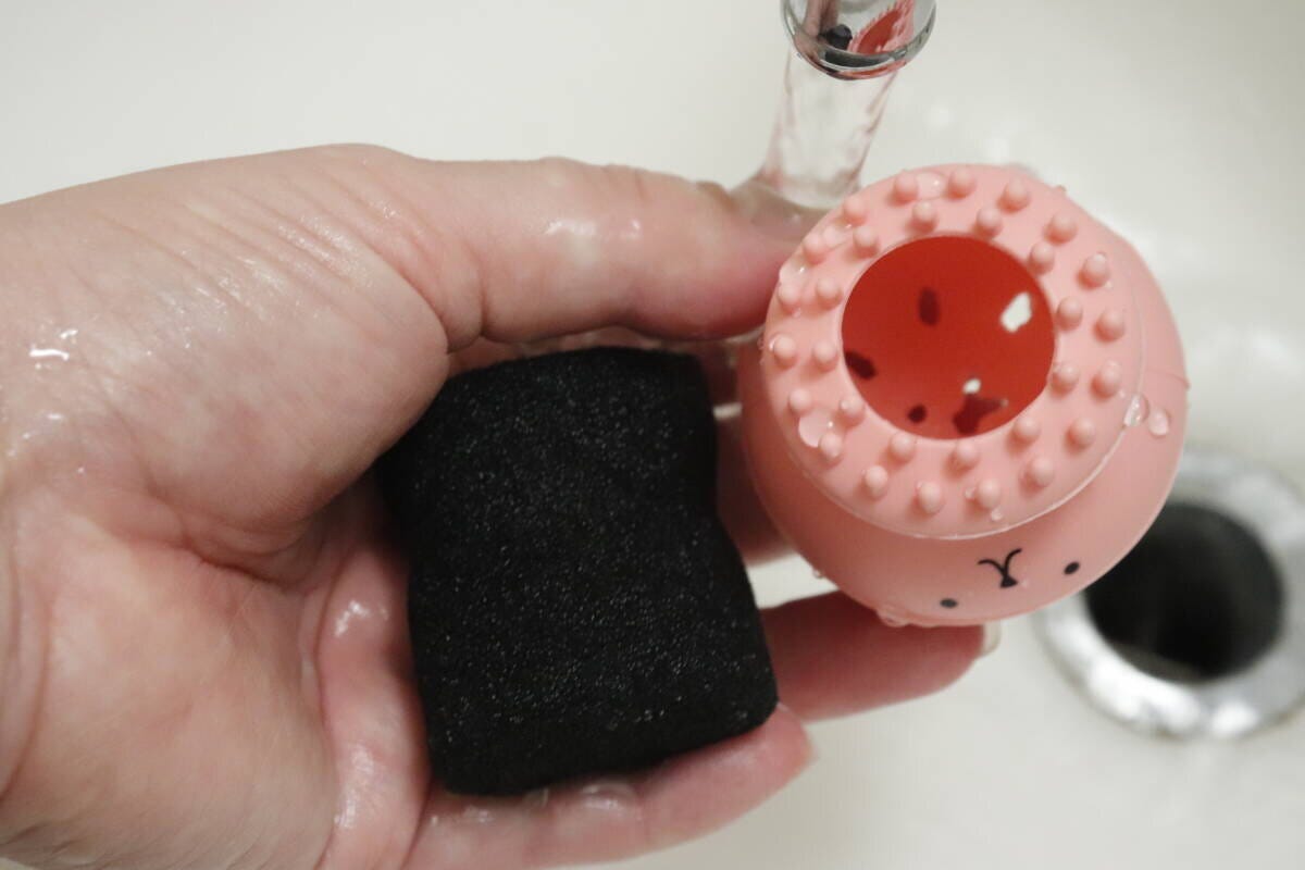 洗顔ブラシから黒いスポンジを取り出し、水で洗っている様子 洗顔ブラシから黒いスポンジを取り出し、水で洗っている様子
