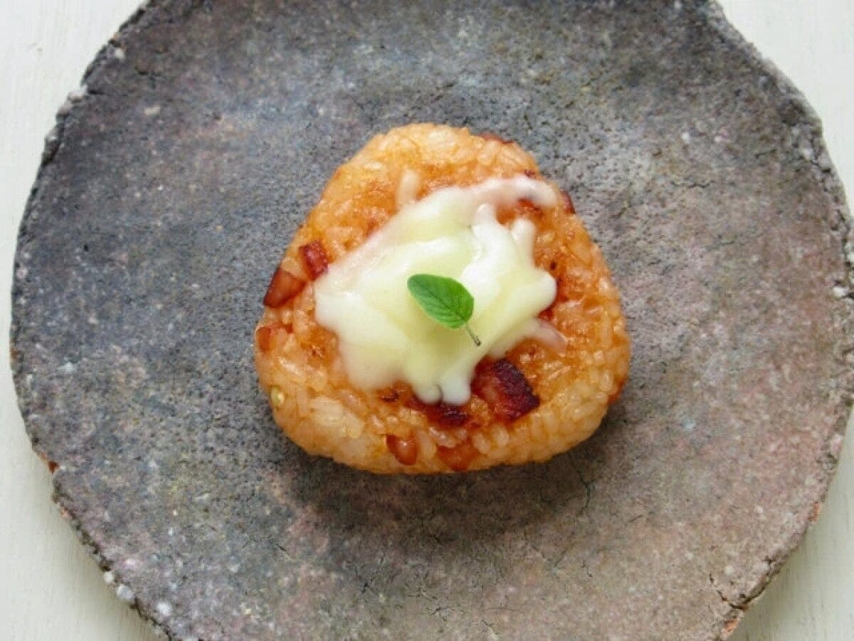 チーズがとろけるケチャップ焼きおにぎり1個がハーブと共に濃いグレーの皿に盛られている