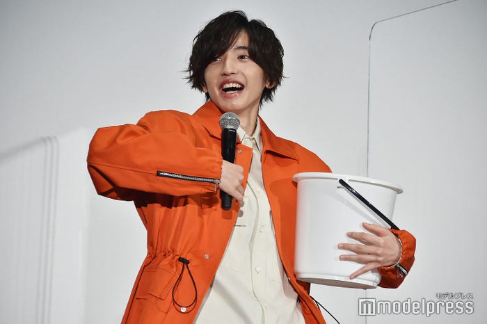 バケツを手に必死にモノボケする道枝駿佑(左手はバケツ、右手はポップコーンを持っている様子を再現)(C)モデルプレス