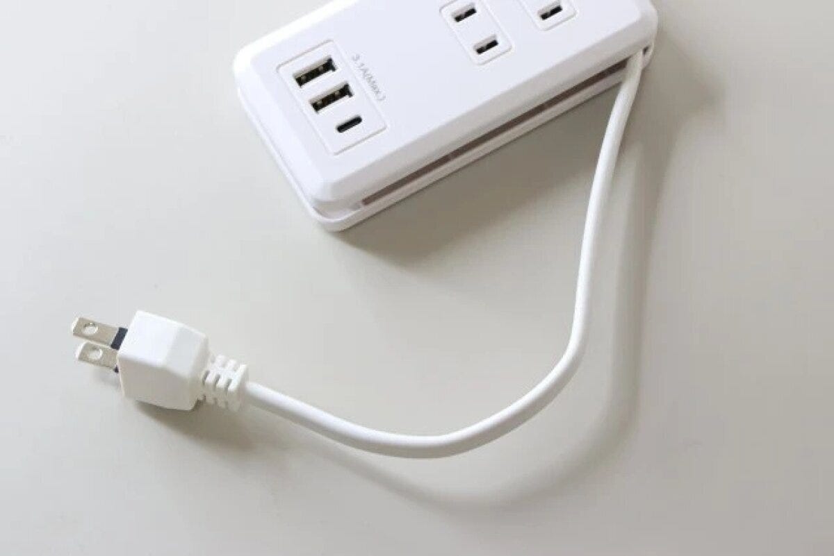 白いコンセントタップの電源コードが本体に巻き付けられ、プラグが収納されている